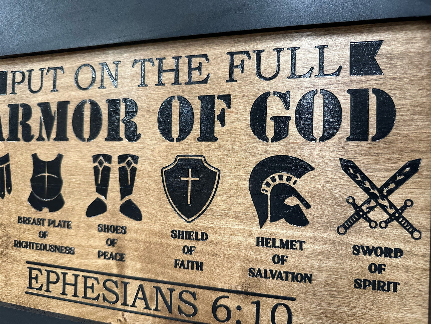 Wooden plaque with engraved symbols and text about the 'Full Armor of God' from Ephesians 6:10.