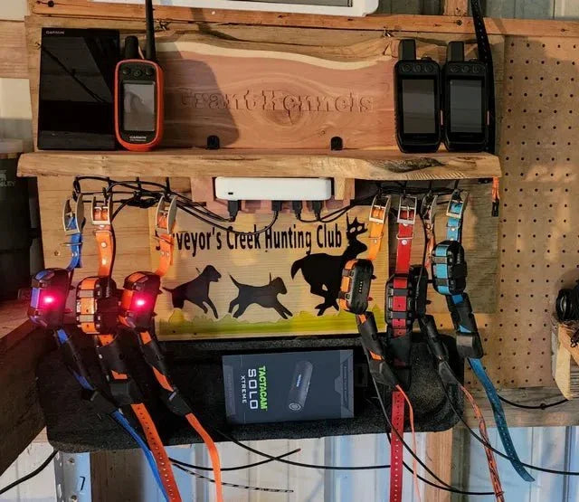 Hunting equipment display with dog collars, GPS devices, and a sign on a wooden shelf.