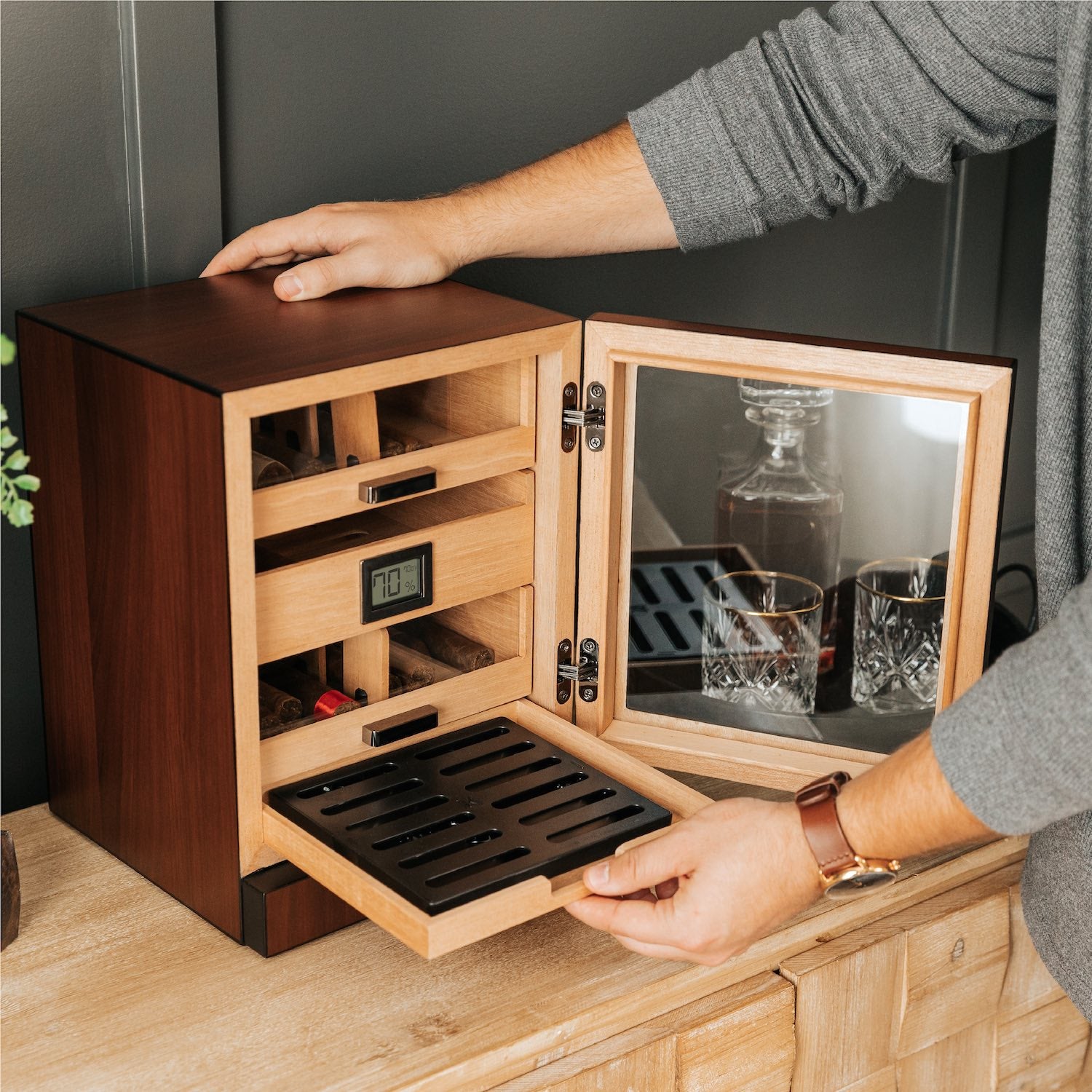 Person interacting with a wooden humidor on a wooden surface.