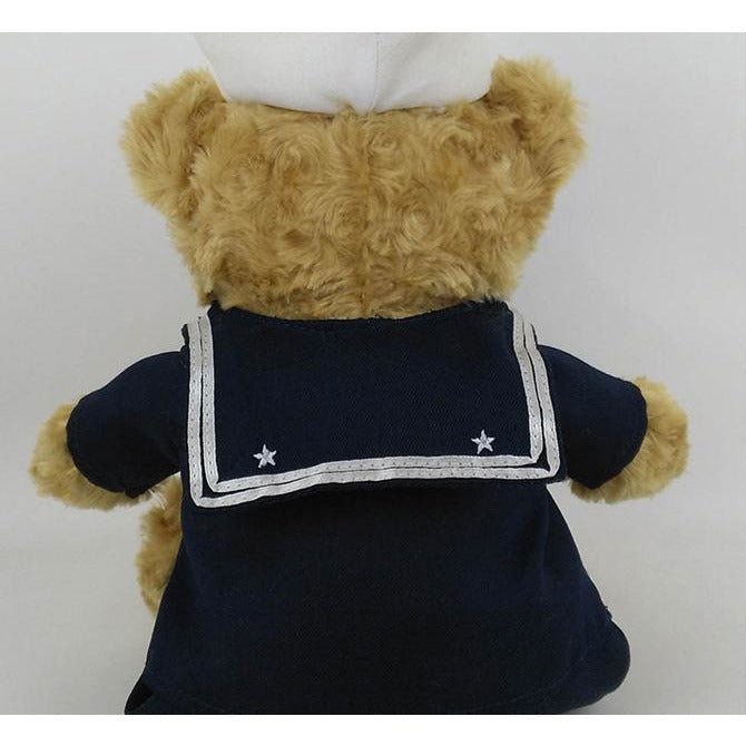 Teddy bear wearing a navy blue sailor outfit with white trim on a white background
