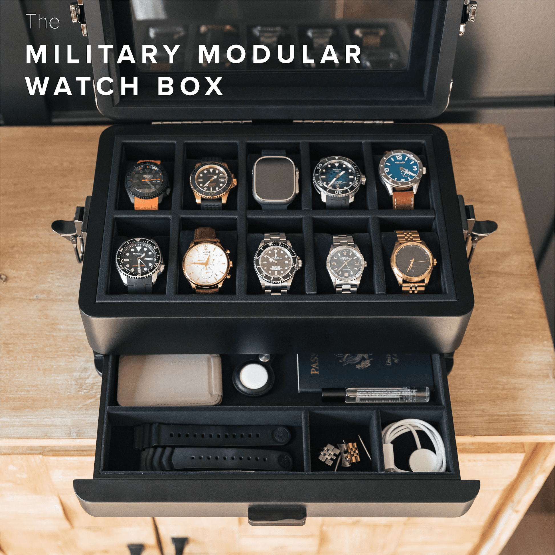 Military modular watch box with multiple watches displayed on a wooden surface