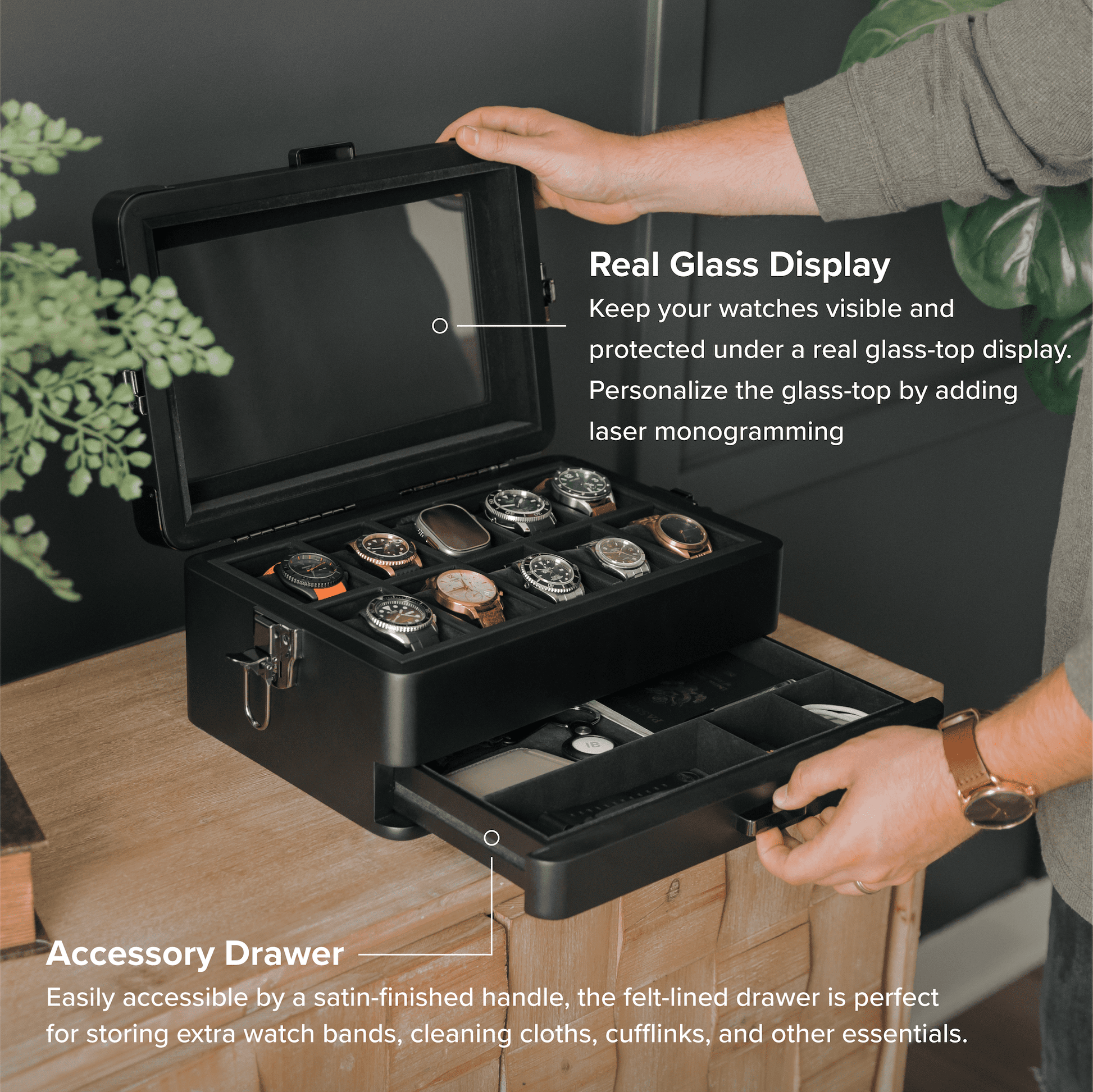 Black watch storage case with glass display and accessory drawer, held by a person.