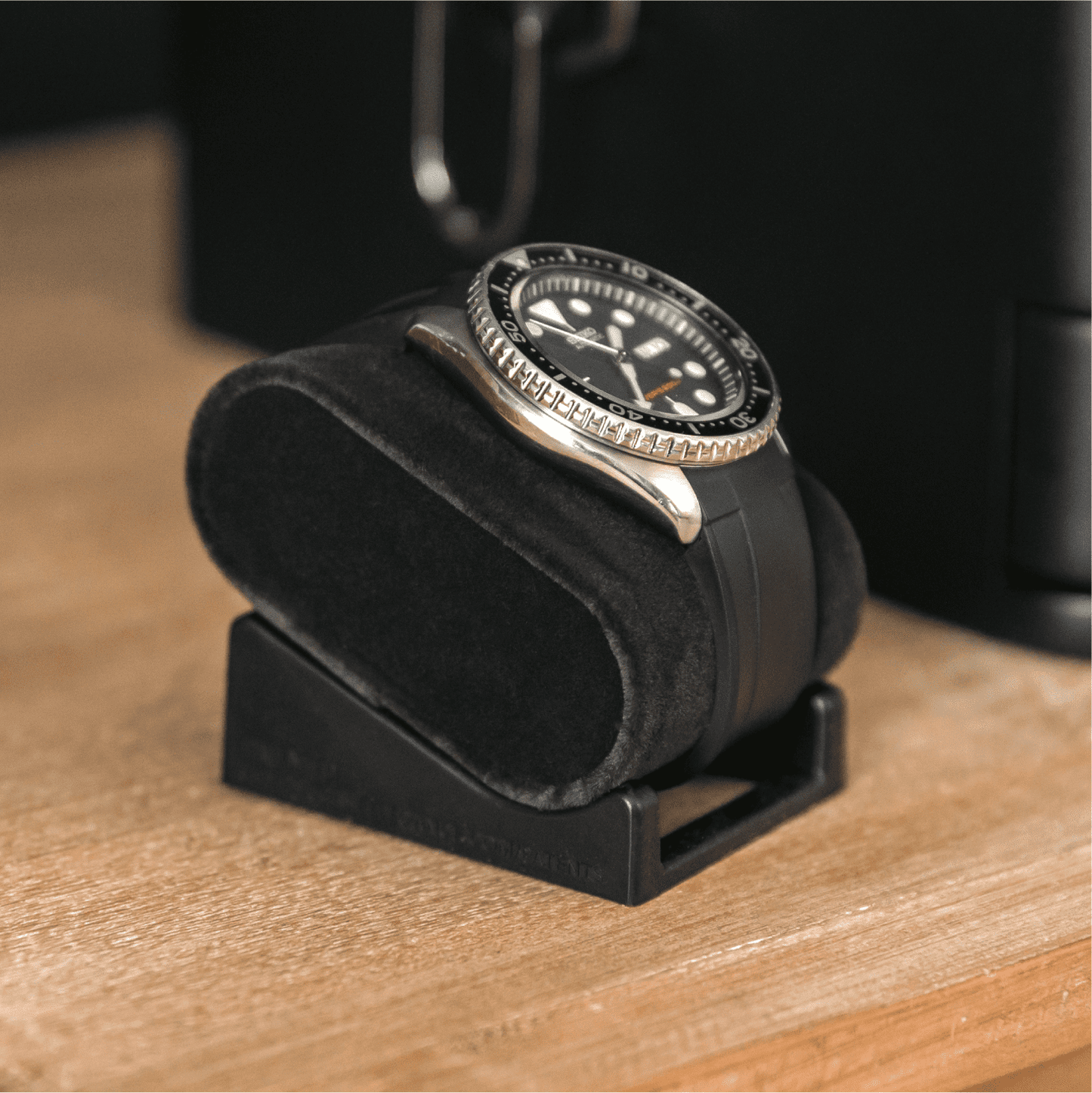 Black watch in a black velvet display case on a wooden surface