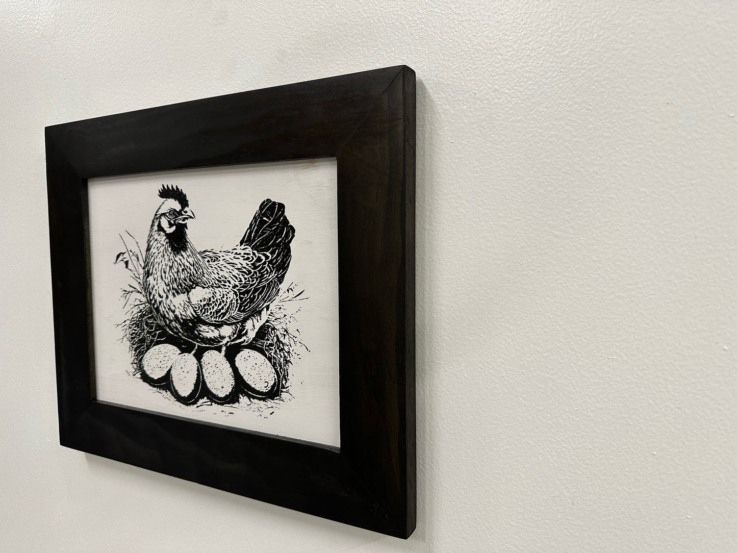 Framed black and white illustration of a rooster on a light gray wall.