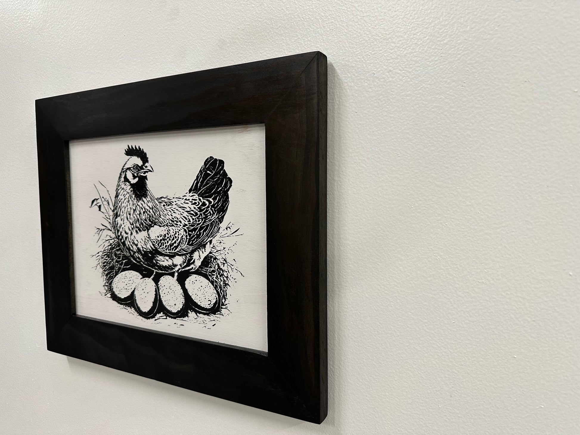 Framed black and white illustration of a rooster on a light gray wall.