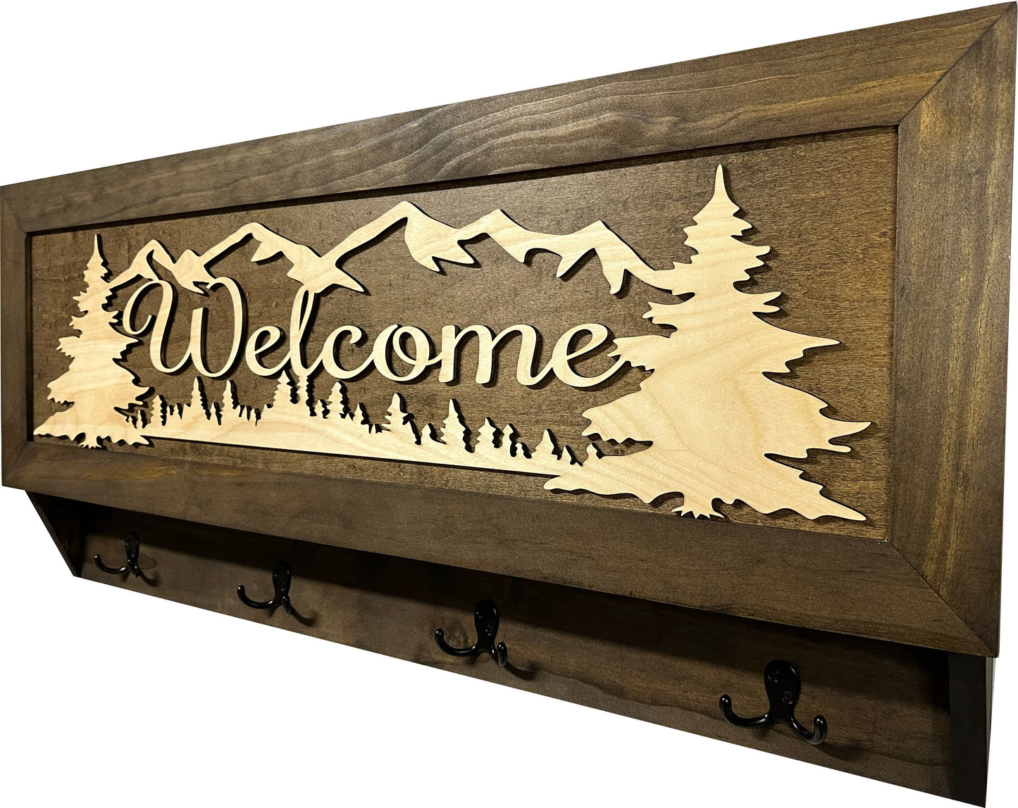 Wooden wall decor with 'Welcome' and mountain design, featuring hooks on a white background.