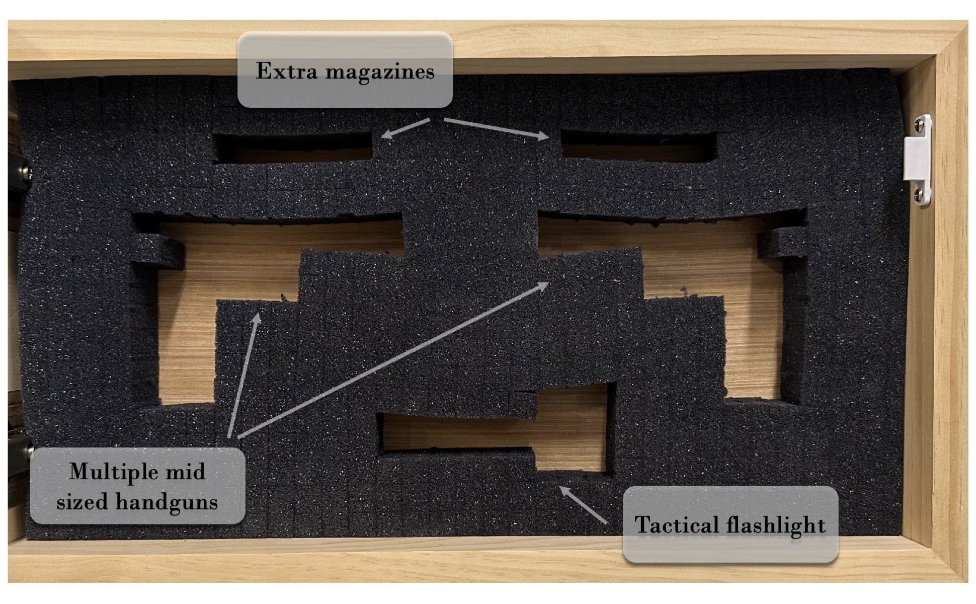 Wooden gun case with foam interior labeled for storage of extra magazines, mid-sized handguns, and a tactical flashlight.
