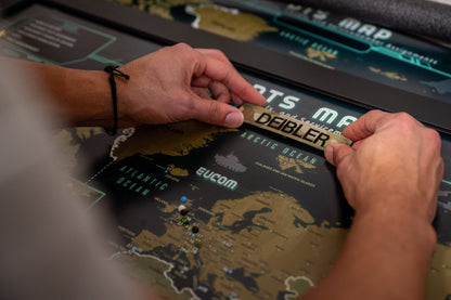 Person interacting with a world map display, focusing on a brand name.