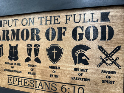 Wooden plaque with engraved symbols and text about the 'Full Armor of God' from Ephesians 6:10.
