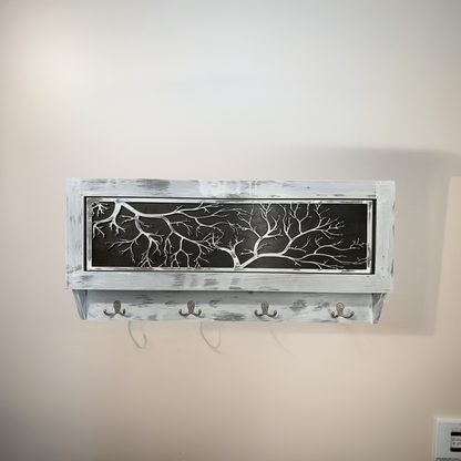 Wall-mounted shelf with decorative metal panel and hooks against a beige wall.