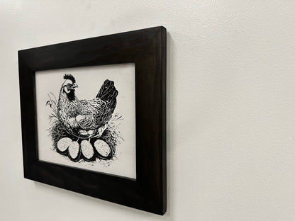 Framed black and white illustration of a rooster on a light gray wall.